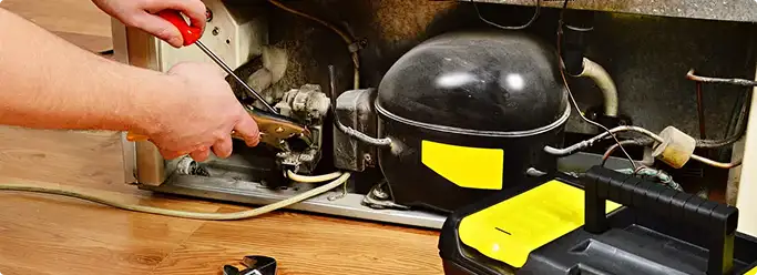 Refrigerator repair technician fixing the compressor and wiring in Rye, CO