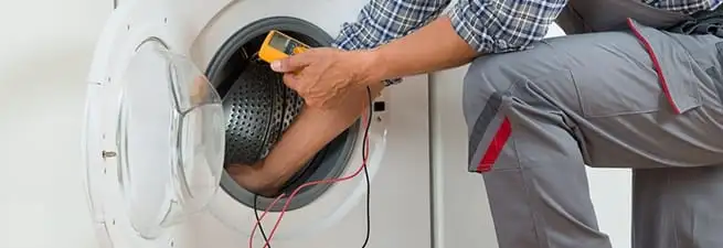Dryer repair technician inspecting and repairing a clothes dryer in Pueblo, CO