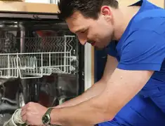 Dishwasher repair technician inspecting and servicing an open dishwasher in Pueblo, CO