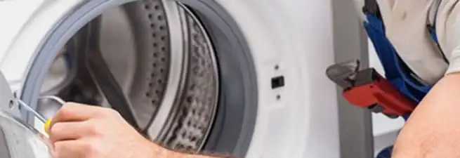 Appliance technician repairing a clothes dryer drum and internal parts in Pueblo, CO