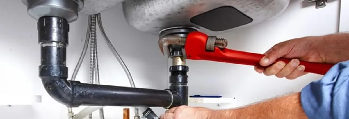 Garbage disposal repair technician tightening the sink drain and disposal connection in Pueblo, CO