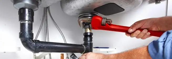 Garbage disposal repair technician tightening the sink drain and disposal connection in Pueblo, CO