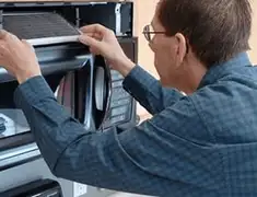 Appliance repair technician replacing a microwave vent filter in Pueblo, CO