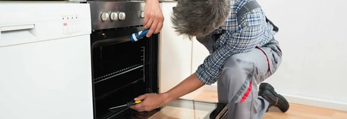Oven repair technician inspecting and servicing an electric oven in Pueblo, CO