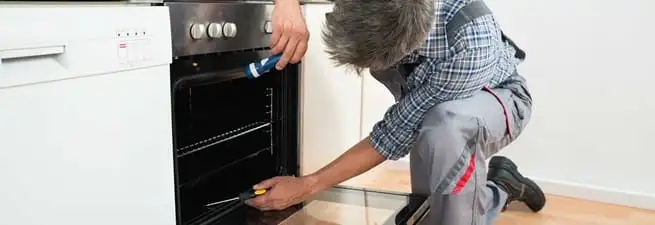 Oven repair technician inspecting and servicing an electric oven in Pueblo, CO