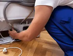 Appliance repair technician fixing refrigerator water line and connections in Pueblo, CO