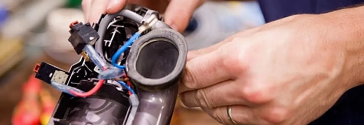 Vacuum repair technician reconnecting wiring and components in Pueblo, CO