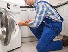 Washing machine repair technician servicing a front-load washer in Pueblo, CO