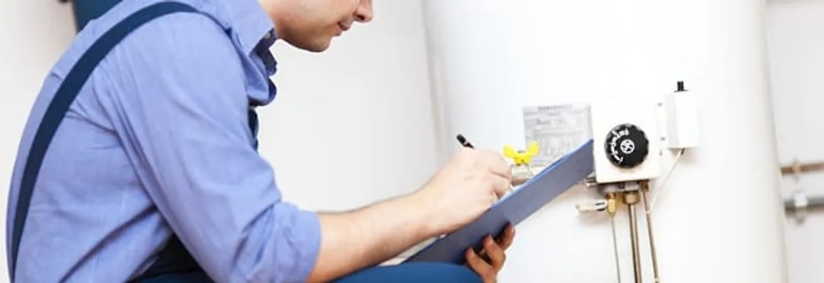 Water heater repair technician inspecting the unit and recording service notes in Pueblo, CO