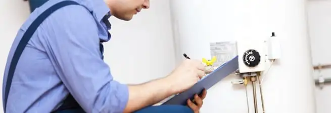 Water heater repair technician inspecting the unit and recording service notes in Pueblo, CO