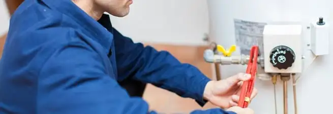 Water heater repair technician adjusting the temperature control and gas valve in Pueblo, CO